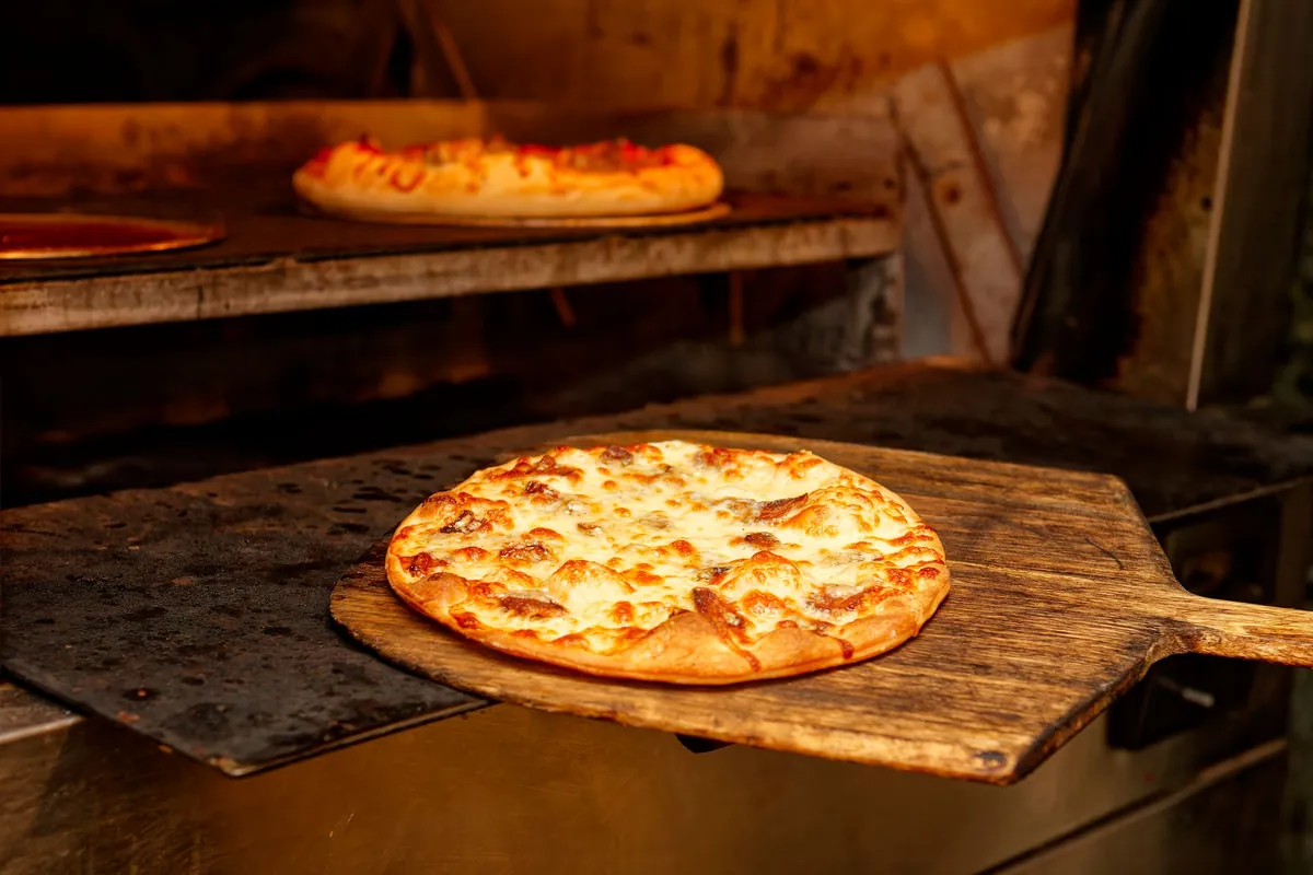 Pizza sulla pala davanti al forno caldo